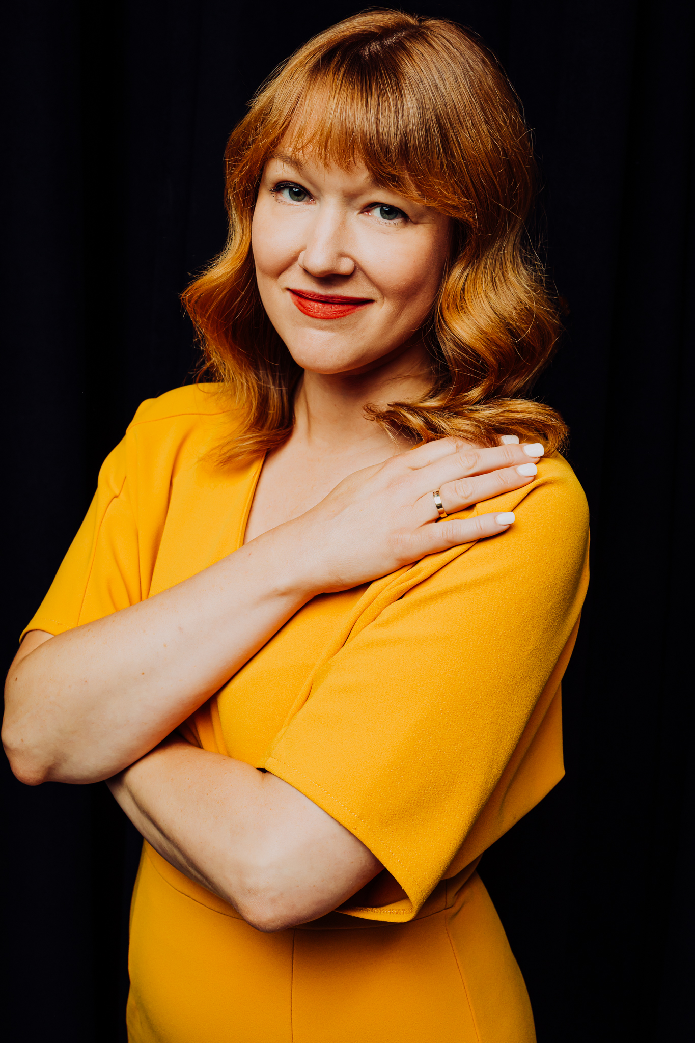 Headshot of woman with red hair wearing a bright yellow dress.